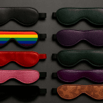A stylish arrangement of various sleep masks in different colors and patterns, including a rainbow design, against a dark background.