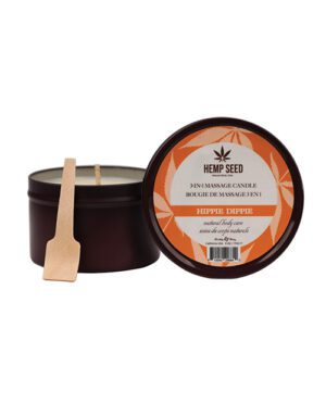 A 3-in-1 massage candle by Hemp Seed in a dark brown container with a wooden application stick, labeled "HIPPIE DIPPIE" and displayed next to its lid which has product information.