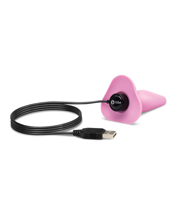 A pink USB rechargeable device connected to a black USB cable on a white background.