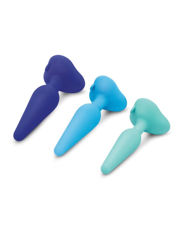 Three silicone spatulas in shades of blue and teal lying on a white surface.