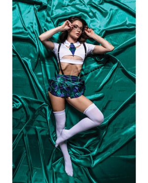 A model posing in a cropped top, plaid skirt, and knee-high socks, lying on a green satin background.