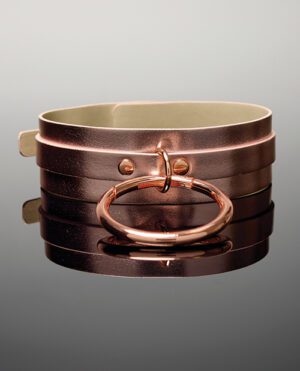 A polished copper bangle with a circular clasp, reflected on a glossy surface.