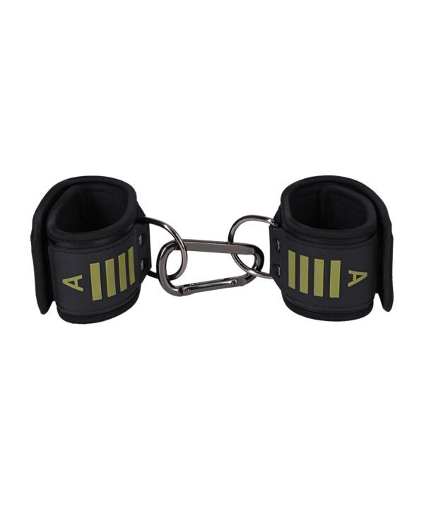 A pair of black wrist cuffs with green detailing designed for strength training isolated on a white background