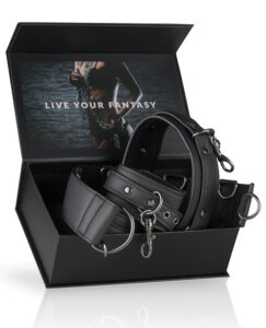 A black leather restraint set displayed in an open box with a provocative background and the text "LIVE YOUR FANTASY."