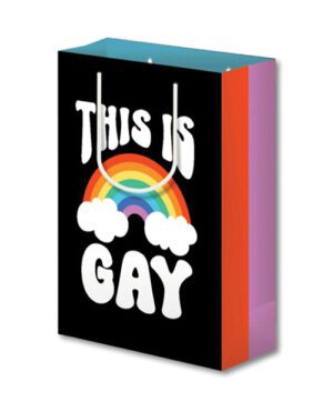 A shopping bag with a rainbow and cloud design and the phrase "This is GAY" written in white block letters on a black background. The sides of the bag have a gradient color scheme ranging from purple to pink to orange.