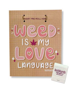 A brown greeting card with "WEED IS MY LOVE LANGUAGE" in pink letters and a slot for inserting a pre-roll, accompanied by a small white product box with the label "kushkards".