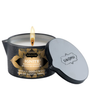 A lit massage candle in a stylish black container with a metal lid, labeled "IGNITE" and featuring a blend of vanilla and sandalwood scents.