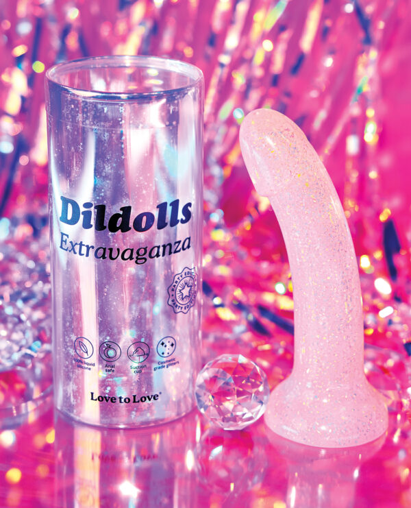 A pink glittery dildo next to its clear packaging on a vibrant, reflective background with sparkling elements.