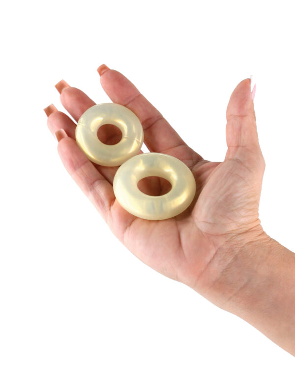 A close-up view of a hand displaying two shiny, translucent donut-shaped objects made of resin.