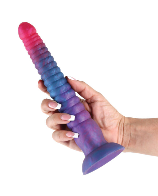 A hand holding a vibrant, textured silicone dildo in gradient shades of pink and blue.