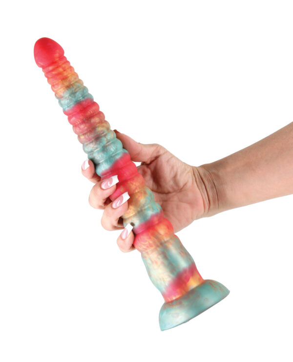 A hand holding a colorful, textured silicone dildo featuring a gradient of red, blue, and yellow shades against a white background.