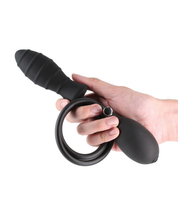 A person holding a black silicone adult toy featuring a textured shaft and a vibrating ring attachment.