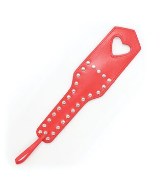 A red leather paddle with a heart-shaped cut-out near the top and two rows of silver studs decorating the surface.