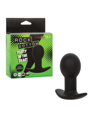 An adult toy known as the "Rock Bottom" next to its packaging which is black and green with text and graphics on it.