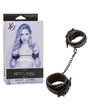 A product photo featuring a box of "Nocturnal Collection Wrist Cuffs" with a picture of a woman on it, alongside a pair of black, heavy-duty, adjustable wrist cuffs connected by a chain.