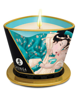 A beautifully designed scented candle featuring a vibrant turquoise and black container adorned with intricate Japanese art, showcasing a romantic scene, and a lit wick.