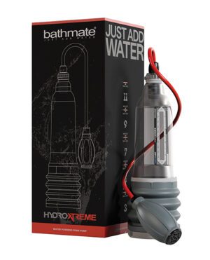 The image shows a product called "Bathmate HydroXtreme" with its packaging. The product appears to be a water-powered penis pump. It is placed next to its black box, which has the product name and "Just Add Water" text on it, along with a graphical representation of the pump. A red tube extends from the pump.