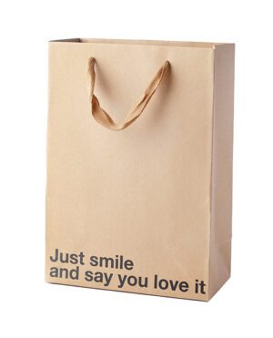 Brown paper bag with twisted paper handles and the phrase "Just smile and say you love it" printed on it.