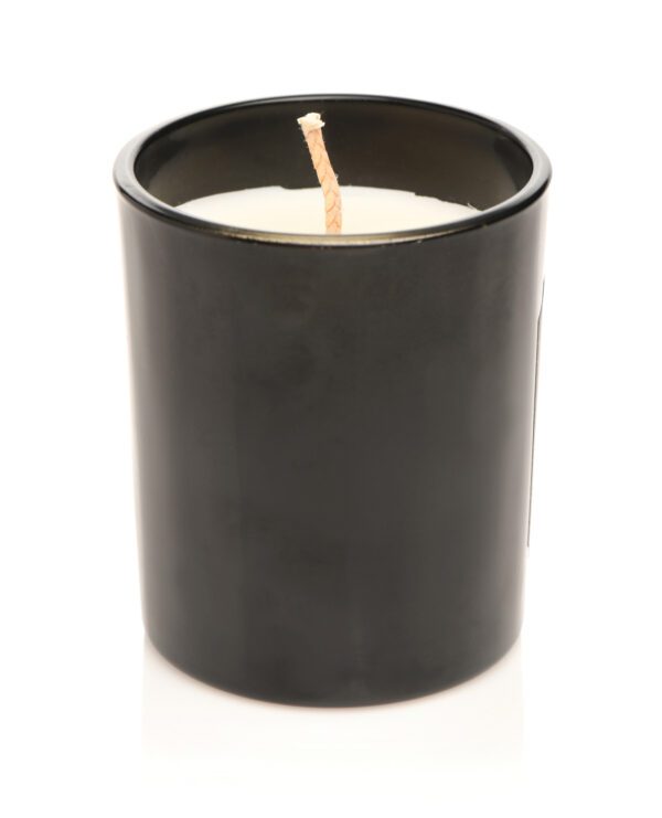 A single wick protruding from a solid white wax inside a sleek black candle container on a white background.