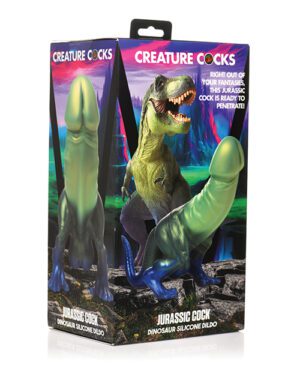 The image is a promotional product photo showing two dinosaur-themed silicone dildos in packaging with the label "Creature Cocks" and the names "Jurassic Cock." The background displays a prehistoric landscape with a T-Rex.