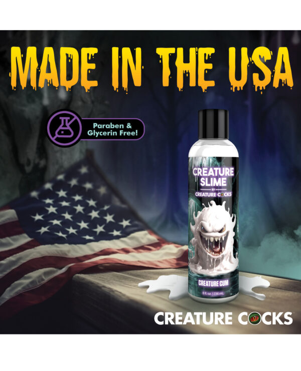 A bottle of "Creature Slime" by Creature Cocks set against a backdrop of the American flag, featuring bold text indicating it's made in the USA and highlighting it as paraben and glycerin free.