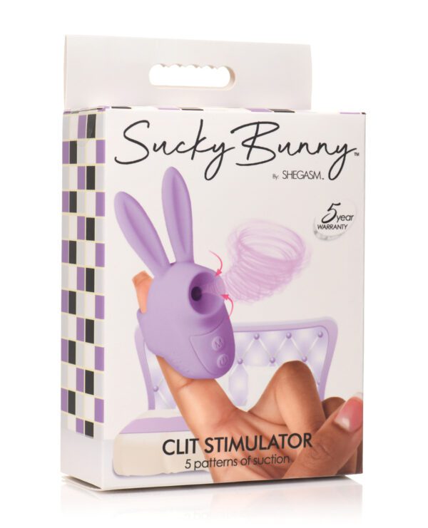 A hand holding the box of a Sucky Bunny Clit Stimulator by SHEGASM with product details and warranty information.